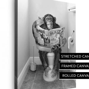 May include: Black and white canvas print featuring a chimpanzee sitting on a toilet, reading a magazine. The print is available in stretched, framed, and rolled canvas options. The magazine cover is visible, with the word "MAD" prominently displayed.