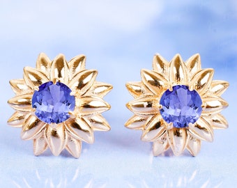 May include: A pair of gold sunflower-shaped earrings with purple gemstones in the center.