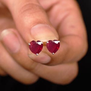 May include: A pair of heart-shaped ruby earrings set in silver.