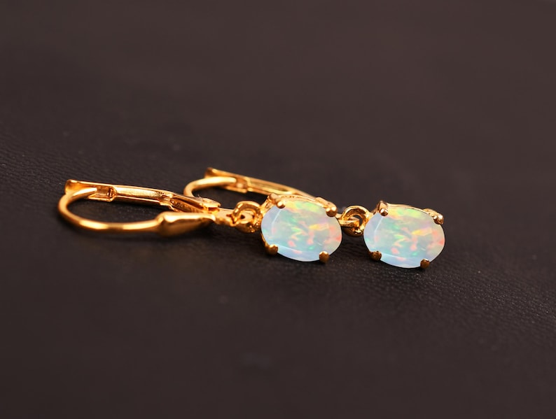 May include: A pair of gold earrings with oval-shaped opal stones. The earrings have a lever back closure.