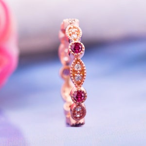 Op de afbeelding: Een roségouden bandring met afwisselende robijn- en diamantstenen gezet in ovale vormen.