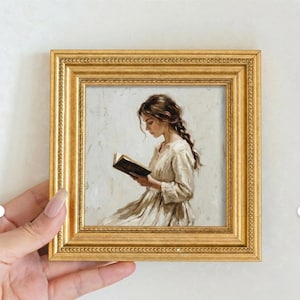 Può includere: Un piccolo dipinto quadrato con cornice dorata raffigura una donna che legge un libro. La donna indossa un abito chiaro e ha lunghi capelli castani intrecciati. Il dipinto ha una tavolozza di colori tenui e uno stile classico.