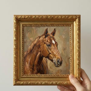 May include: Oil painting of a brown horse's head with a white blaze, set in a gold ornate frame. The artwork features detailed brushstrokes and a neutral background, creating a classic equestrian theme.