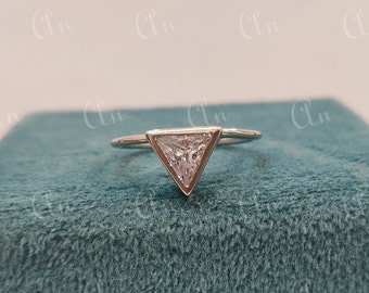 May include: A silver ring with a triangular shaped clear gemstone.