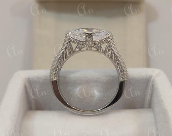 May include: A silver engagement ring with a large, clear, oval-shaped center stone. The ring has a delicate, intricate design with small diamonds set in the band.