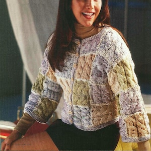 Könnte beinhalten: Ein mehrfarbiger Strickcardigan mit Knopfleiste. Der Cardigan ist aus einem dicken Garn gefertigt und hat ein Patchwork-Design. Der Cardigan wird von einer Person mit langen braunen Haaren getragen.