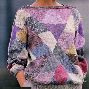 Puede incluir: Un suéter de punto morado, azul, blanco y rosa con un patrón geométrico. El suéter tiene cuello de barco y mangas largas.
