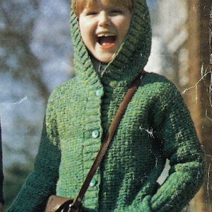 May include: A green hooded cardigan with a button-up front and pockets. The cardigan is worn with a brown leather satchel. The person in the image is smiling and wearing a black skirt.