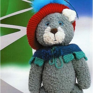 May include: A gray crocheted cat toy wearing a red hat with blue feathers, a blue and green scarf, and yellow and black boots.
