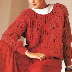 May include: A red knitted sweater with a lacy pattern. The sweater has a round neckline and long sleeves.