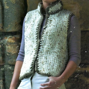May include: A white and brown knitted waistcoat with a button fastening. The waistcoat has a high collar and a textured knit pattern.
