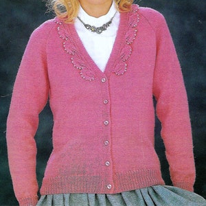 May include: A pink knitted cardigan with a V-neck and button closure. The cardigan has a decorative beaded trim around the neckline.