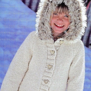 May include: A cream-colored knitted cardigan with a fur-trimmed hood and cuffs. The cardigan has a button closure with heart-shaped buttons.