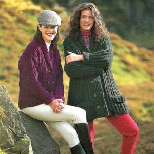 Könnte beinhalten: Zwei Frauen tragen Strickjacken. Eine Frau trägt eine lila Strickjacke und eine weiße Hose, die andere trägt eine grüne Strickjacke und eine rote Hose. Beide Frauen tragen schwarze Stiefel.