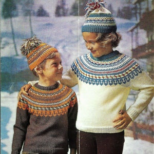 May include: Two children wearing knitted sweaters with colorful patterns and matching knit hats with pom-poms. The sweaters have a traditional Scandinavian design.