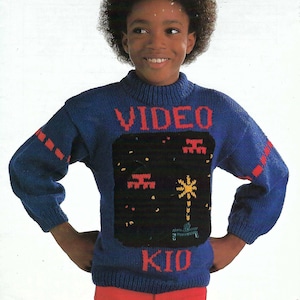 May include: A blue knitted sweater with a red "VIDEO KID" graphic and a pixelated video game scene on the front.
