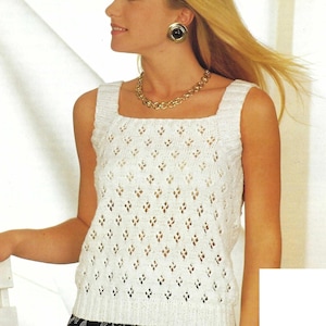 May include: A white, sleeveless knit top with a square neckline and diamond-shaped cutouts. The top is paired with a gold necklace and earrings. The model is wearing a black and white patterned skirt.
