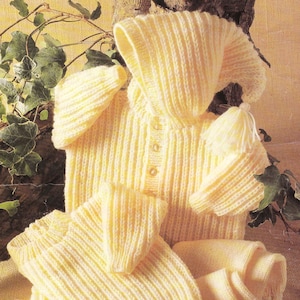 May include: A set of knitted baby clothes in a pale yellow color. The set includes a hooded jacket, a pair of pants, and a hat.