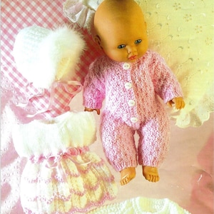 Può includere: Un set di vestiti di maglia per bambole in rosa e bianco, tra cui un vestito, un cardigan, un cappello e stivaletti. I vestiti sono realizzati con un punto testurizzato e hanno un aspetto delicato e femminile.