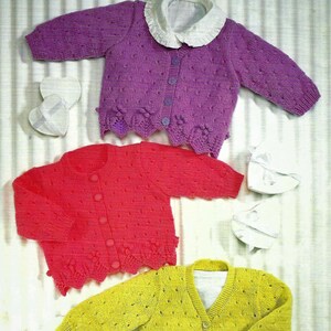 May include: Three knitted baby cardigans in purple, red, and yellow with button fastenings. Each cardigan has a scalloped hem and a white collar.