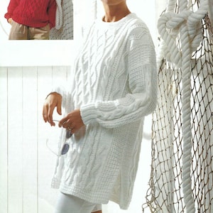 May include: A white cable-knit jumper with a crew neck and long sleeves. The jumper has a textured pattern and a split hem. A smaller image shows a red cable-knit jumper. The background includes a white wall, a fishing net, and a thick rope.
