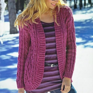 May include: A pink cable knit cardigan with a deep V-neck and long sleeves. The cardigan is worn over a striped shirt and a black belt.
