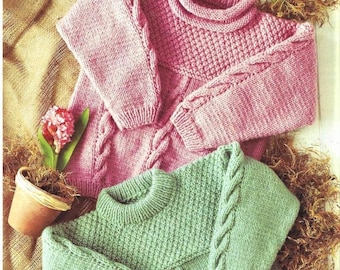 May include: Two knitted sweaters, one pink and one green, with a cable knit pattern. The sweaters are folded and displayed on a burlap background.