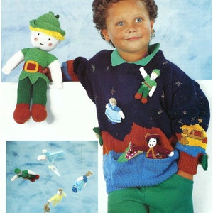 Könnte beinhalten: Ein blauer Strickpullover mit einer Tasche und mehreren angestrickten Figuren. Die Figuren umfassen ein Mädchen in einem blauen Kleid, einen Jungen in einem grünen Outfit und einen Jungen in einem roten und goldenen Outfit. Der Pullover hat ein Sternenmuster und einen roten, orangen und gelben Streifen am unteren Rand.
