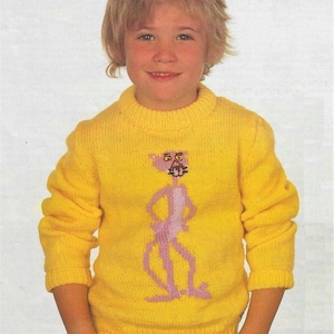 May include: A yellow knitted jumper with a pink cartoon character on the front. The character is standing with its arms crossed and has a surprised expression on its face.