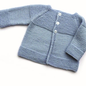 May include: A light blue knitted baby cardigan with a button fastening.