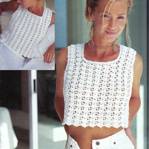 Può includere: Un top bianco senza maniche all'uncinetto con scollatura quadrata e orlo smerlato. Il top presenta un motivo floreale dettagliato. L'immagine mostra il top indossato con pantaloni bianchi.