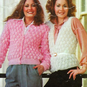 Puede incluir: Dos mujeres con suéteres de punto. La mujer de la izquierda lleva un cárdigan rosa con cierre de botón. La mujer de la derecha lleva un chaleco blanco con cinturón.