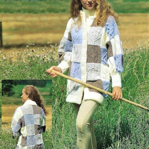 May include: A white, blue and brown knitted cardigan with a chunky knit pattern. The cardigan is shown on a model in a field of green grass. The cardigan is 32-42 inches (81-107 cm).