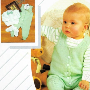 May include: A green knitted baby onesie with a white striped top and buttons down the front. The onesie is worn by a baby sitting on a white and green striped blanket with a teddy bear.