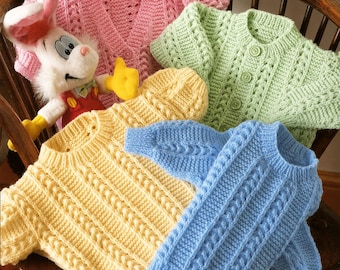May include: A collection of colorful, hand-knitted baby sweaters and a matching hat in pink, yellow, green, and blue. The sweaters feature cable knit and textured patterns. A plush bunny toy with a red vest and yellow gloves is also in the image.
