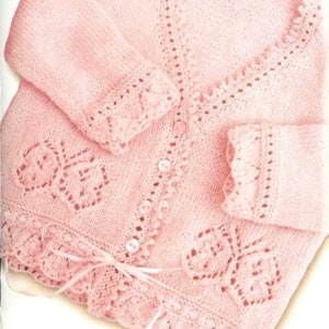 May include: A pink knitted cardigan with a lace pattern and a tie at the waist.