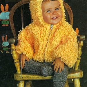 Könnte beinhalten: Ein Kind trägt eine gelbe Kapuzenjacke mit Reißverschluss und grauer Strickhose. Die Jacke hat ein strukturiertes, geschlungenes Design. Das Kind lächelt. Dekorative Hasen-Ausschnitte sind im Hintergrund.