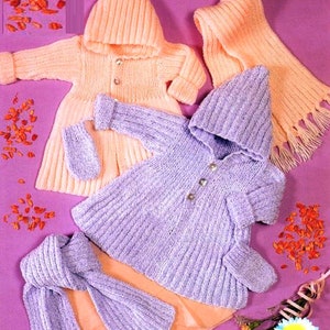 Puede incluir: Dos conjuntos de punto para bebé, uno en melocotón y otro en lavanda, cada uno con una chaqueta con capucha, guantes a juego y una bufanda. Los conjuntos están dispuestos sobre un fondo rosa. 16-24 pulgadas.