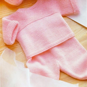 Puede incluir: Un conjunto de bebé de punto rosa con un jersey de manga larga y pantalones. El jersey tiene una banda de contraste alrededor de la cintura.