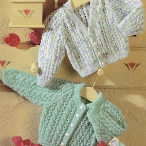 May include: Two knitted baby cardigans, one in a light blue and white colour with a cable knit pattern and the other in a light green colour with a cable knit pattern.
