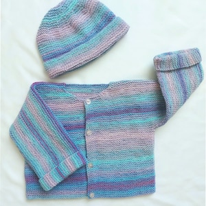 May include: A striped knitted baby cardigan with a matching hat in shades of blue, purple, and pink. The cardigan has a button closure.