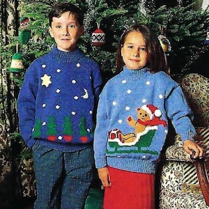 Peut inclure: Deux enfants portant des pulls de Noël bleus avec des motifs festifs. Le pull du garçon représente une étoile, une lune et des sapins. Le pull de la fille représente un ours en peluche dans un traîneau.