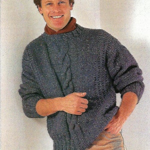 Op de afbeelding: Een donkerblauwe gebreide trui met een kabelbreisel. De trui heeft een ronde hals en lange mouwen.