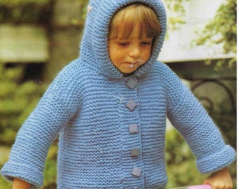 May include: A blue knitted hooded cardigan with a button closure and decorative stitching on the hood. The cardigan is worn by a child holding a pink and white toy.
