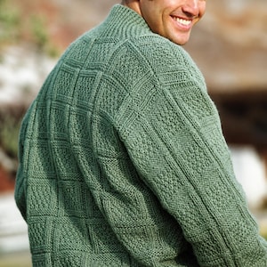May include: A green knit sweater with a textured pattern. The sweater has a high collar and a detailed design across the front and sleeves. The knitwear appears to be a medium weight.