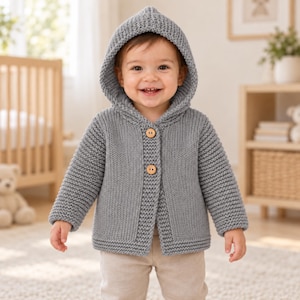 May include: A light grey knitted hooded cardigan featuring a textured garter stitch pattern, long sleeves, and two round wooden buttons down the front. The garment has a thick ribbed border along the opening and hem, providing a structured look.