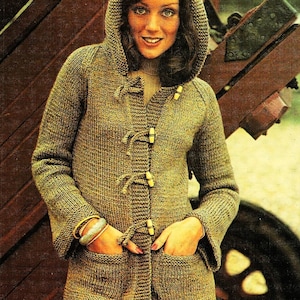 Könnte beinhalten: Ein brauner Kapuzenpullover mit Strickstruktur und Holz-Knöpfen. Der Pullover hat zwei Taschen und wird von einer Person mit braunen Haaren getragen.