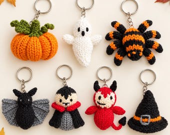 May include: A collection of seven crocheted keychains featuring Halloween themes, including an orange pumpkin with green leaves, a white ghost, a black and orange spider, a black bat, a vampire, a red devil, and a black witch hat with an orange band.