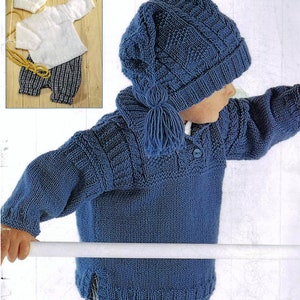 May include: A knitted blue child's outfit, comprising a hat with a tassel, a sweater with a buttoned collar, and matching shorts. The shorts have a blue and white checked pattern. The outfit is made of textured yarn.
