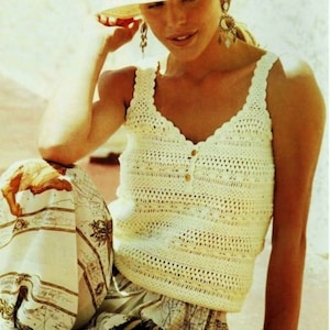 May include: A woman wearing a white crochet tank top with a button fastening and a white crochet hat. She is wearing a printed skirt and bracelets on her wrist.